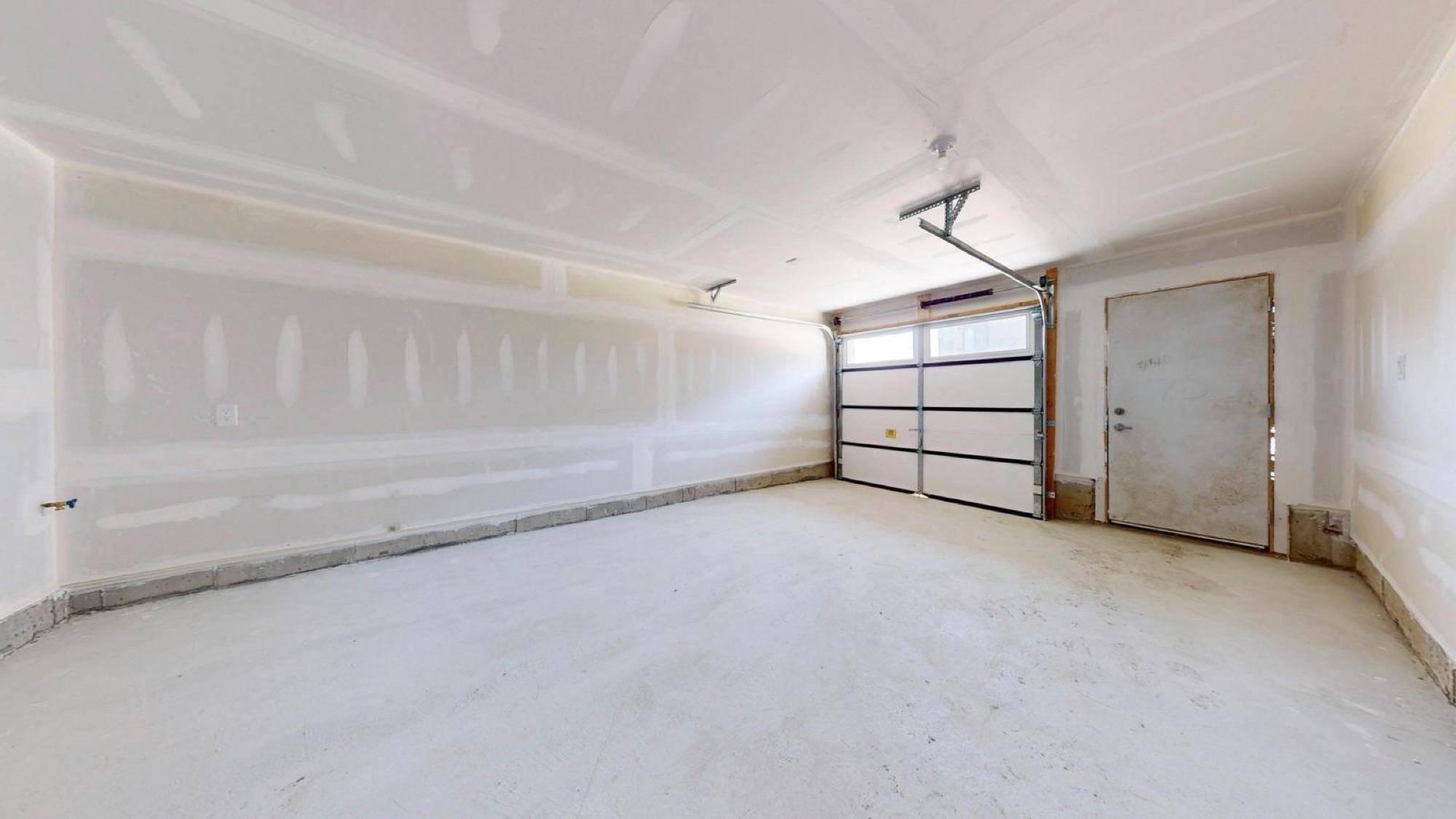 A garage boarded and taped to the ceiling, still on bare concrete before floor and paint